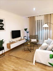 ein Wohnzimmer mit einem weißen Sofa und einem TV in der Unterkunft As Conchas in Vilagarcia de Arousa