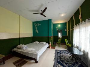 a bedroom with a bed and a green wall at Resort Green Earth in Tajpur