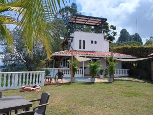 une maison blanche avec une clôture blanche et une table dans l'établissement Finca con vista al embalse y jacuzzi, à Guatapé