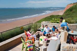 a group of people sitting on a wall near the beach at 3 Bedroom Deluxe Caravan at Haven Devon Cliffs in Exmouth
