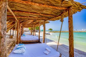 una fila de camas en una playa con el océano en Marazao Beach Hotel & Spa en Tierra Bomba