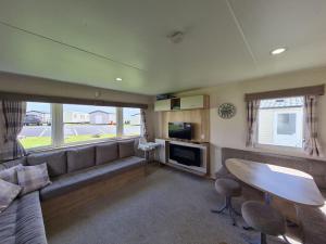 uma sala de estar com um sofá e uma mesa em 3 Bedroom Deluxe Caravan at Haven Devon Cliffs em Exmouth