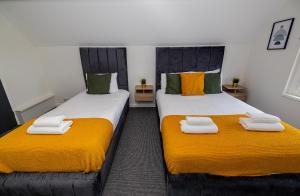 two beds in a room with orange and white towels at Woodford Hotel in London