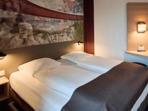 a large white bed in a hotel room at B&B HOTEL Vejle in Vejle