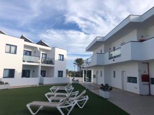 a row of lounge chairs on a lawn in front of a building at Casa Sofia - Costa Calma Sun & Beach in Costa Calma