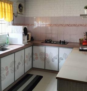 a kitchen with white cabinets and a microwave at Homestay Cikgu in Pasir Gudang