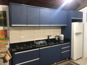 cocina con armarios azules, fregadero y nevera en Cabana parque en Antônio Prado