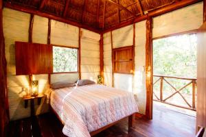 a bedroom with a bed in a room with windows at Selvaluna cabaña eco-chic in Tulum +62 photos