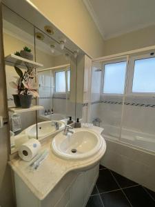 a white bathroom with a sink and a shower at Wanderlust House in Ponta Delgada