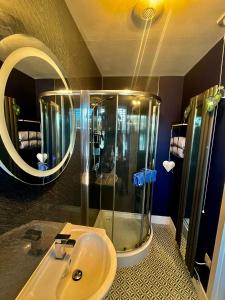 uma casa de banho com um chuveiro, um lavatório e um espelho. em The Lodge Dunrowan em Kyle of Lochalsh