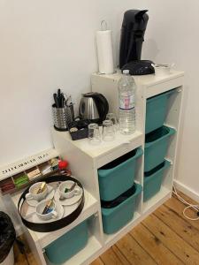 un estante blanco con platos y botellas de agua. en studio indépendant sans cuisine - Le coin cosy avec WIFI, en Bruselas