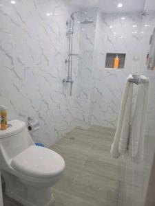y baño blanco con aseo y ducha. en Obynb en Santo Domingo