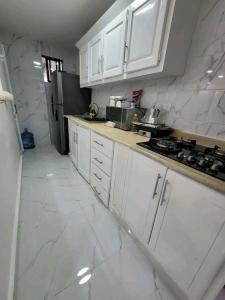 a white kitchen with white cabinets and a refrigerator at Obynb in Santo Domingo