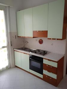 uma cozinha com armários brancos, um fogão e um lavatório em Il Cortile em Brugherio
