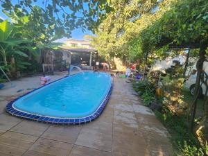 a swimming pool in a yard with people around it at Mini Chácara Cristo Redentor in Marechal Deodoro