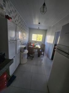 eine Küche mit weißen Geräten und ein Esszimmer mit einem Tisch in der Unterkunft Mini Chácara Cristo Redentor in Marechal Deodoro