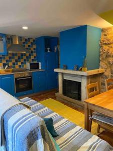 une cuisine bleue avec une table et une cheminée dans l'établissement Gerês Country Stays - Palheiro, à Rio Caldo