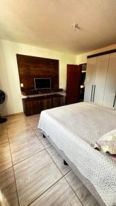 um quarto com uma cama e uma televisão de ecrã plano em Cantinho Feliz - Próximo ao Centro histórico em Tiradentes