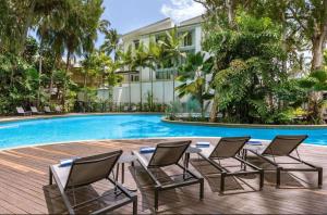 a table and chairs next to a swimming pool at Palm Cove Beachside Apartments - Sea and Mountain Views in Palm Cove