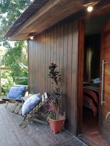 a wooden cabin with a bed and a bench on a patio at CASA JANE in Imbituba