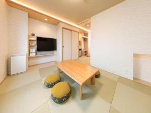 a living room with a wooden table and two stools at Tokai City Hotel in Tokai