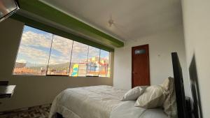a bedroom with a bed and a large window at Waylla Hostel in Huaraz