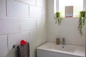 baño con lavabo y pared de ladrillo blanco en Joseph Retreat, en Avarua