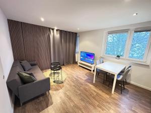 a living room with a couch and a table and a tv at Modern 2 Bedroom Apartment near train station in Eichwäldchen