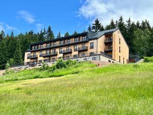 a building on top of a hill with a field at Apartmán s terasou Benecko in Benecko