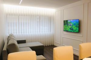 uma sala de estar com um sofá e uma televisão na parede em G 0.8 - G.oogle Nest Smart House em Braga