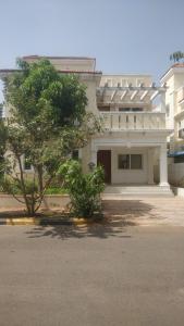 a white building with a tree in front of it at Gardenia Groove Villa, Ramky Discovery City in Maisaram
