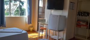 a kitchen with a refrigerator and a table and a window at HOTEL TROPICAL in Curitiba