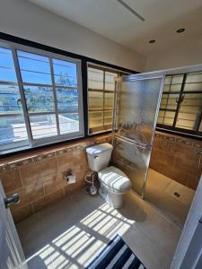 ein Bad mit einem WC, einer Dusche und Fenstern in der Unterkunft Penthouse con Jacuzzy en Santo Domingo in Cancino