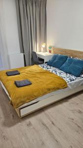1 dormitorio con 1 cama grande con manta amarilla y almohadas azules en Villa Neptun Apartament nad morzem Gdańsk Wyspa Sobieszewska, en Gdansk