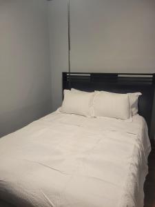 ein weißes Bett mit einem schwarzen Kopfteil und weißen Kissen in der Unterkunft Cozy apartment in Chicago