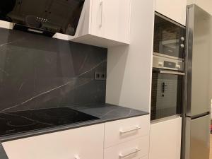 a kitchen with white cabinets and a black counter top at Valencia beach rooms in Valencia