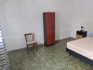 1 dormitorio con 1 cama, 1 silla y 1 armario en Departamento Jorge en Marcos Juárez