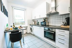 cocina con electrodomésticos blancos, mesa y ventana en Zentral-Kingsize Bett-Playstation 4-HBF nach Köln und Düsseldorf, en Haan