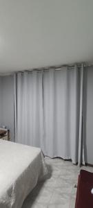 um quarto com cortinas brancas e uma cama em Casa completa em Marília