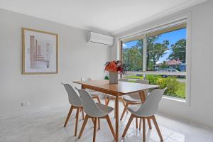 a dining room with a table and chairs and a window at Discover Mount Annan - Spacious 6-BR House in Narellan