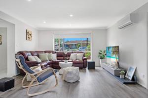 a living room with a couch and a tv at Discover Mount Annan - Spacious 6-BR House in Narellan