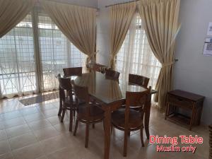 una mesa de comedor y sillas en una habitación con ventanas en 892 Villa Dfaro Afamosa Melaka en Melaka