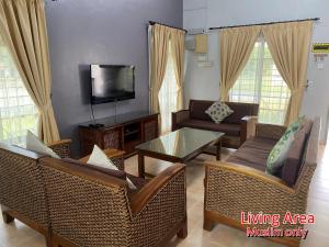 sala de estar con muebles de mimbre y TV en 892 Villa Dfaro Afamosa Melaka en Melaka