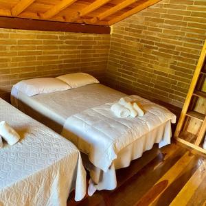 Habitación con 2 camas y pared de ladrillo en Villetta Gramado Florença en Gramado