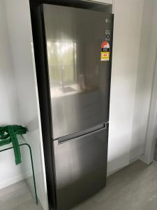 a stainless steel refrigerator in a kitchen next to a wall at 424 Trees Tiny Home in Tallebudgera