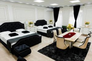 two beds in a room with a table and chairs at Pensiunea Infinity in Târgu Jiu