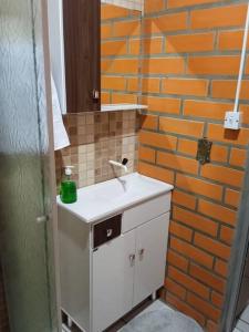 uma casa de banho com um lavatório e uma parede de tijolos em Casa Tia Dori em Rio Forcação