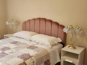 a bed with a pink headboard and two tables with lamps at Comfortable entire 3BDR Apt in Laval Montreal in Laval