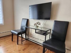 拉瓦尔Comfortable entire 3BDR Apt in Laval Montreal的两把椅子和一张玻璃桌,墙上有电视