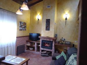 a living room with a fireplace and a tv at casa rural EL RINCON in Navadijos